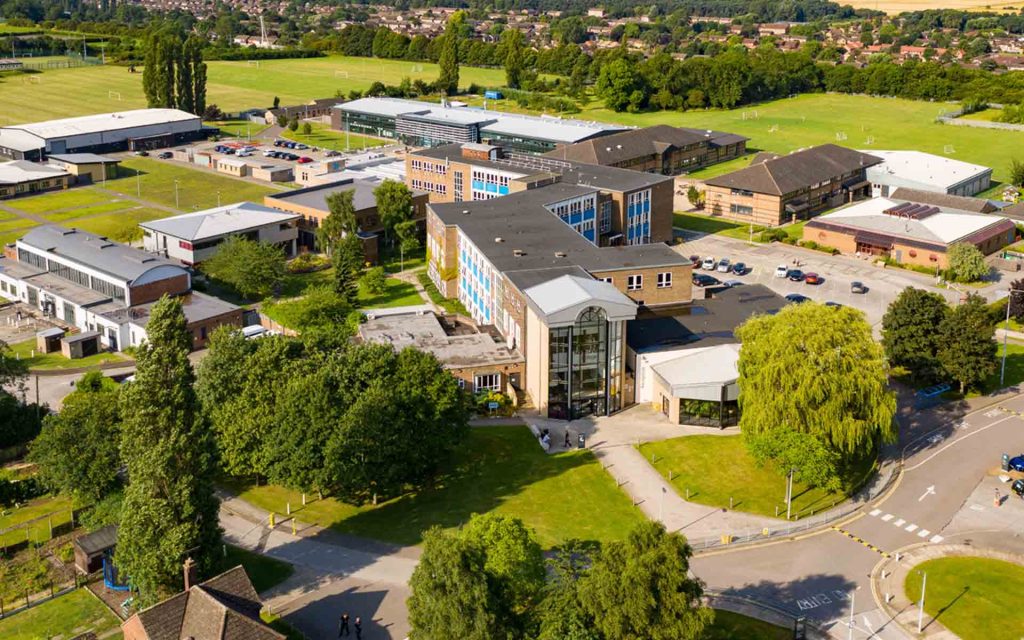 An aerial view of our entire North Lindsey College campus. On a sunny day the campus buildings can be seen set in vibrant green fields surrounding and full, tall trees dotted throughout the grounds.